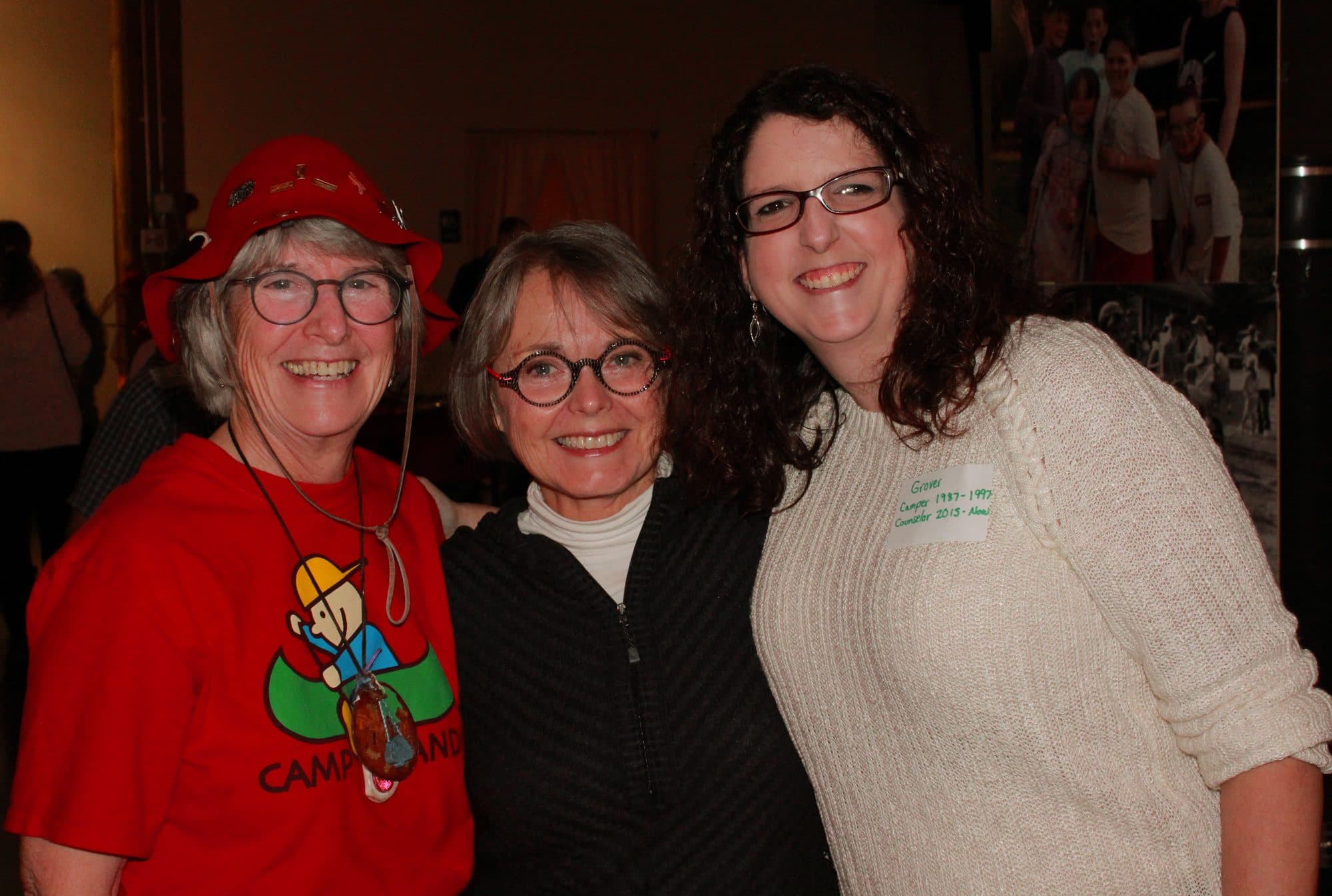 Three people smiling together indoors